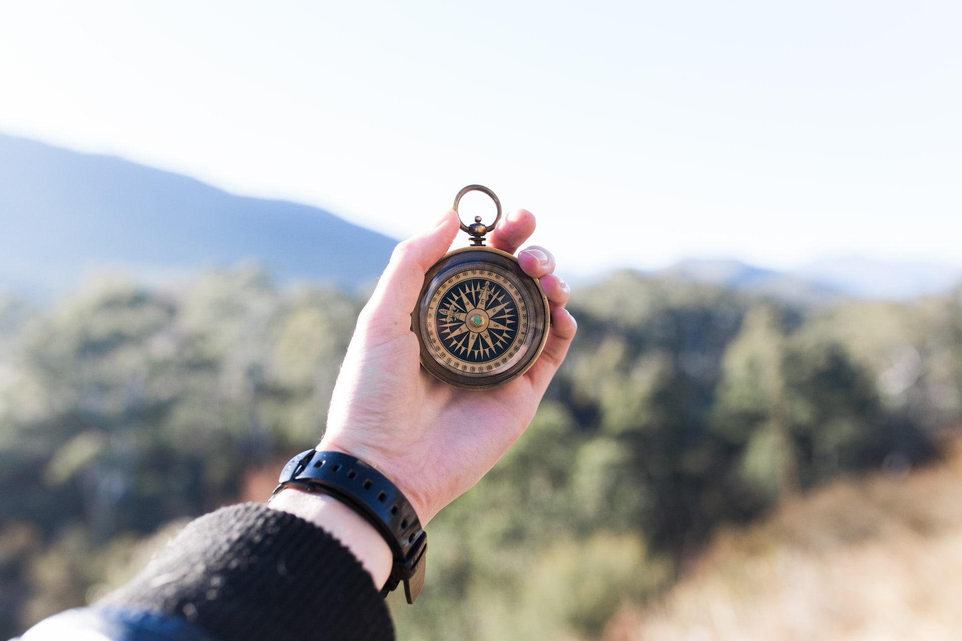 person holding compass selective focus photography